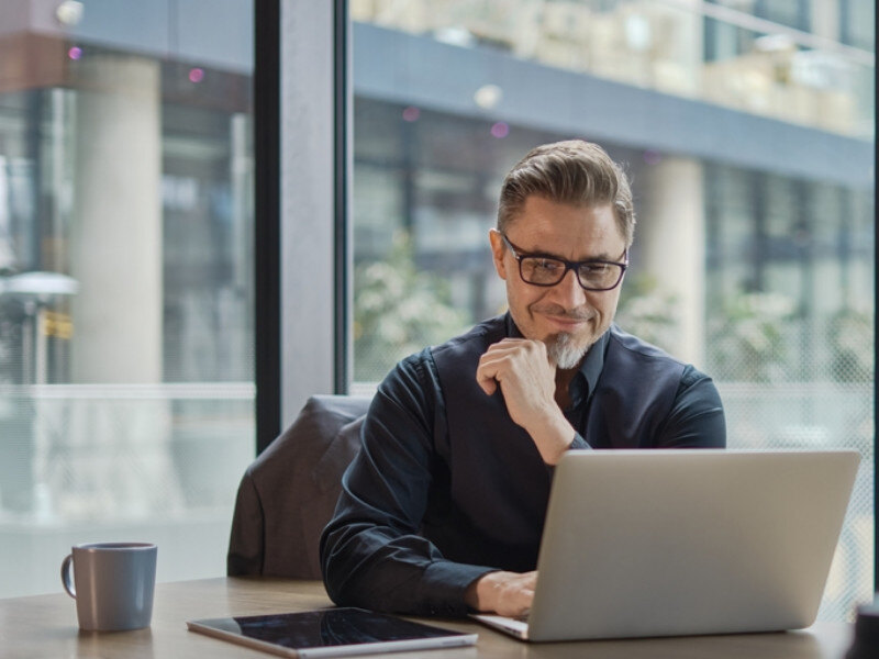 man smiling at laptop in conference room