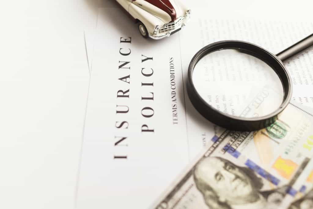 insurance policy with magnifying glass and $100 bill