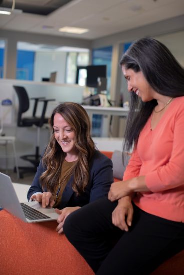 women talking by a laptop in an office